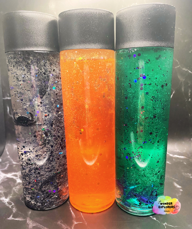 Three sensory bottles in black, orange and green